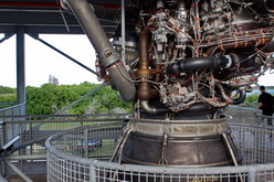 Jeden ze tří hlavních motorů raketoplánů (SSME - Space Shuttle Main Engine). V pozadí raketoplán Discovery.